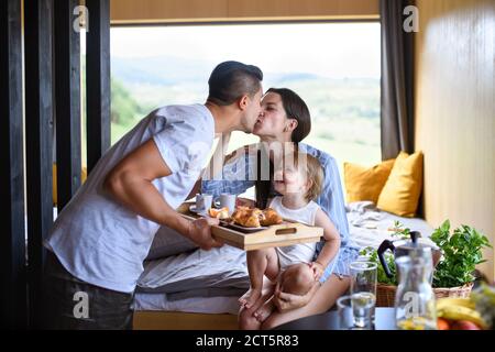 Jeune famille avec petite fille à l'intérieur, week-end loin dans la maison de conteneurs dans la campagne. Banque D'Images