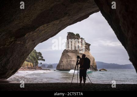 Photographe prenant une photo à Cathedral Cove, péninsule de Coromandel, Île du Nord de la Nouvelle-Zélande Banque D'Images