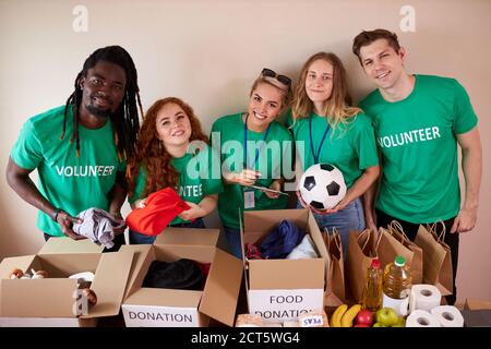les jeunes actifs aiment faire du bénévolat à la banque de nourriture et de vêtements, en compagnie de bénévoles. diverses personnes travaillant en compagnie de bénévoles avec des amis de mettre Banque D'Images