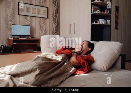 Femme malade et grippe. Pris au froid. Femme se sentant froide avec une couverture reposant sur le canapé à la maison Banque D'Images