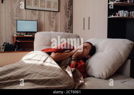 Femme malade et grippe. Pris au froid. Femme se sentant froide avec une couverture reposant sur le canapé à la maison Banque D'Images