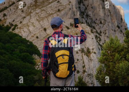 Homme puissant randonneur prenant des photos avec un smartphone au sommet de la montagne. Une merveilleuse pause. Le concept d'activité et la disponibilité de la connexion mobile Banque D'Images