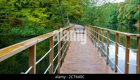 Pont suspendu et chemin de randonnée en bois au-dessus du lac une soirée d'automne Banque D'Images