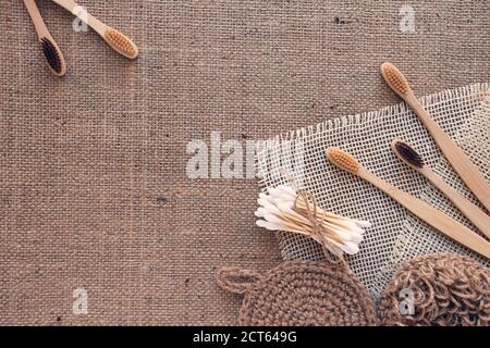 Outils de salle de bain naturels, concept durable zéro déchet et style de vie. Brosses à dents en bois, écouvillons en bambou et débarbouillettes en jute faites à la main sur tissu Banque D'Images