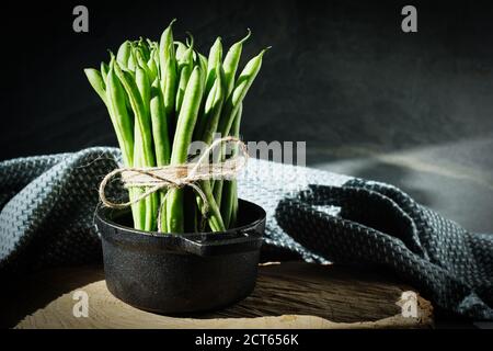 Grains fraîchement récoltés, attachés avec une corde dans un pot en fonte sur une plaque en bois avec fond noir Banque D'Images