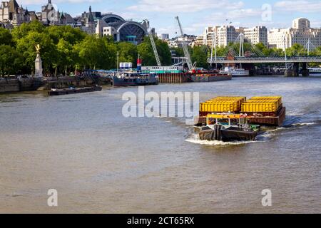 Remorqueur tirant le fret comme conteneurs dans un grand séparé Péniche le long de la Tamise à Londres Banque D'Images