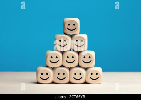 Icônes de visage souriant sur des cubes en bois. Évaluation du service d'affaires, satisfaction de la clientèle ou concept de travail d'équipe. Banque D'Images