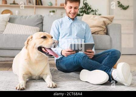 Homme à la maison avec tablette numérique et labrador Banque D'Images