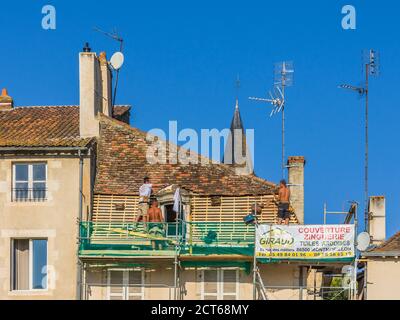 Ouvriers de toitures remplaçant lattes en bois et tuiles en argile sur le vieux bâtiment - Montmorillon, Vienne (86), France. Banque D'Images