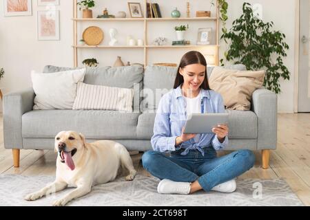 Jeune femme à la maison avec une tablette et un chien Banque D'Images