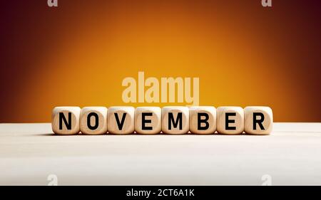 Le mois de novembre écrit sur des cubes en bois avec un arrière-plan d'automne avec espace de copie. Mois de l'année. Banque D'Images
