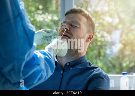 test nasal du coronavirus - travailleur de laboratoire prenant un mucus échantillon provenant du nez du patient mâle Banque D'Images