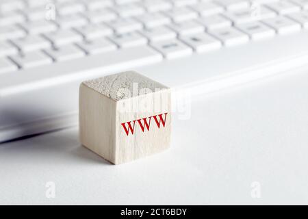 Le mot www, World Wide web écrit sur un bloc de bois avec un arrière-plan de clavier d'ordinateur. Concept de communication en ligne ou de navigation Web. Banque D'Images