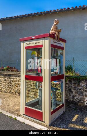 Ancien téléphone utilisé comme bibliothèque publique gratuite avec modèle elf sur le toit - Saulgé, Vienne (86), France. Banque D'Images