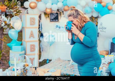 Femme enceinte prenant des photos d'une table décorée pour la douche de bébé. Photocamera, décorations de fête en blanc et bleu, bébé garçon Banque D'Images