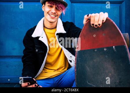 Portrait d'un jeune garçon adolescent alternatif joyeux et joyeux avec skateboard et téléphone cellulaire - concept de personnes de diversité et jeunesse style de vie - b Banque D'Images