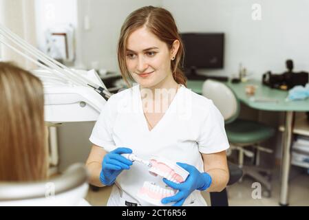 Dentiste montrant au patient comment se brosser les dents en clinique dentaire. Banque D'Images