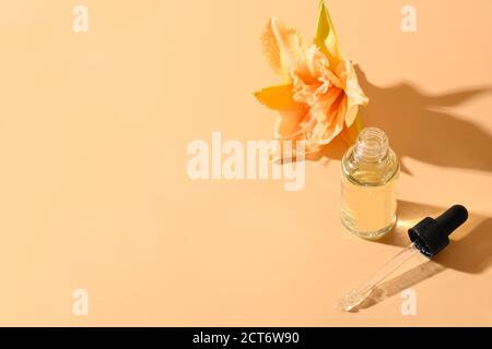 Huile ou essence cosmétique en bouteille de verre avec fleurs de nénuphars fraîches sur fond beige. Vue de dessus. Gros plan. Banque D'Images