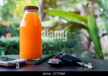 Jus d'orange fraîchement pressé dans une bouteille avec smartphone et les touches Banque D'Images