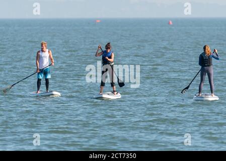 Southend on Sea, Essex, Royaume-Uni. 21 septembre 2020. Le temps a fait sombre et nuageux à Southend sur la mer, mais a éclaté dans un après-midi chaud et ensoleillé. Les gens sont dehors en appréciant la marée haute de l'après-midi avec un peu de prendre à l'eau. Un mâle et deux femelles sont sur des planches de paddle dans une rangée. Trois personnes paddle-board Banque D'Images