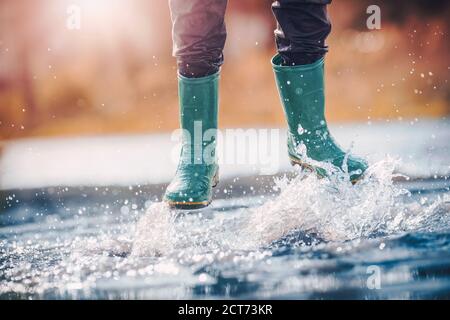 La marche de l'enfant dans la flaque en wellies sur temps de pluie Banque D'Images