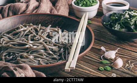 Reste de la vie des nouilles soba japonaises traditionnelles avec du nori (algues comestibles) et de la sauce soja, sur une surface en bois de près avec une attention sélective Banque D'Images