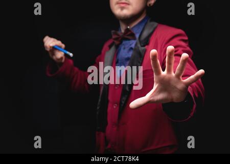 Homme magicien avec baguette magique sur fond noir Banque D'Images