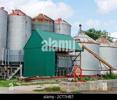 Le panneau indiquant foin et Bois de chauffage est affiché devant deux rangées de silos métalliques sur une ferme. Les silos sont visiblement abîmés et rouillés. Dans le backgroun Banque D'Images