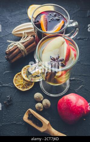 Deux verres de différents type de vin chaud ou de gluhwein basé sur les vins rouge et blanc avec des épices et ingrédients sur fond noir. Chaud épicé bever Banque D'Images