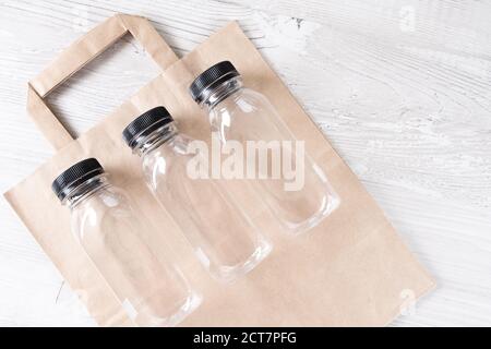 maquette, créateur de scène. sac en papier, trois bouteilles en plastique. Emballage alimentaire écologique et sacs écologiques en coton sur fond gris avec espace de copie Banque D'Images