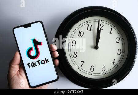 Stafford / UK - septembre 21 2020: TikTok et l'horloge, concept. Le logo TikTok vu sur le smartphone tient dans une main et l'horloge analogique à côté. Banque D'Images