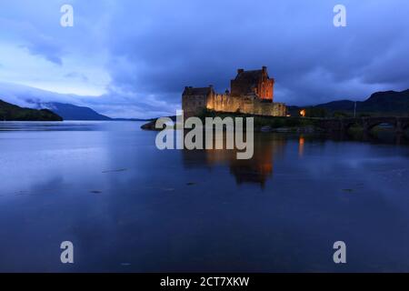 Eileen Donan Castle a illuminé après le coucher du soleil, dans une soirée nuageux, West Highlands, Écosse, Royaume-Uni Banque D'Images