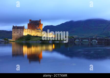 Eileen Donan Castle a illuminé après le coucher du soleil, dans une soirée nuageux, West Highlands, Écosse, Royaume-Uni Banque D'Images