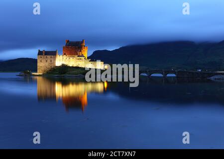 Eileen Donan Castle a illuminé après le coucher du soleil, dans une soirée nuageux, West Highlands, Écosse, Royaume-Uni Banque D'Images