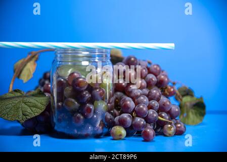 Grappes de raisins de table. Fruits pour la consommation fraîche. Raisins pour la vinification. Arrière-plan bleu et flou artistique. Fruits avec de grandes baies avec un framboise Banque D'Images