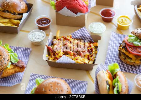 Disposition du restaurant Burger avec des frites au fromage et au bacon placées sur une surface en bois clair. Banque D'Images