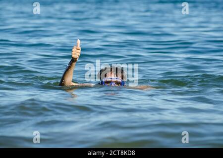 Femme avec masque de plongée dans l'eau et montrant le pouce vers le haut. Banque D'Images