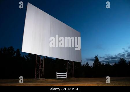 Écran de cinéma blanc vierge avec drive-in ; ciel nocturne en arrière-plan. Banque D'Images