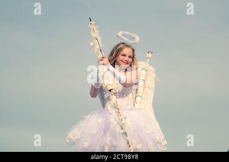 Flèche d'amour. Portrait d'une petite fille cupid. cupid ado mignon sur le nuage - ciel arrière-plan. Innocent fille avec ailes d'ange debout avec l'arc et Banque D'Images