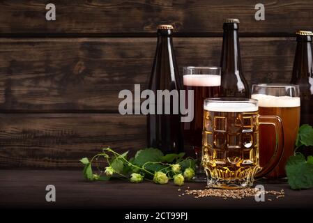 Différentes sortes de bière pression en bouteilles, verres et mug sur table en bois, espace de copie. Bière fraîche brassicole au houblon et au malt. Banque D'Images