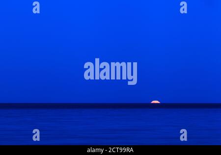 Pleine lune sur la mer le long de la mer Baltique. Ciel bleu et lune montante. Banque D'Images