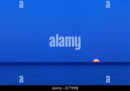 Pleine lune sur la mer le long de la mer Baltique. Ciel bleu et lune montante. Banque D'Images