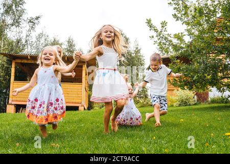 Des enfants heureux qui s'amusent dans le jardin sur l'herbe. Heure d'été. Banque D'Images