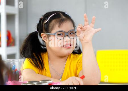 Bonne fille asiatique avec le syndrome de Down en classe. Banque D'Images