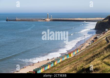 Chalets de plage le long de Whitby Sands menant à l'entrée du port de la ville de pêche. Banque D'Images