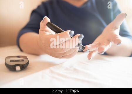 La femme utilise le glucomètre pour vérifier le taux de sucre dans le sang pour le diabète, les taux d'insuline Banque D'Images