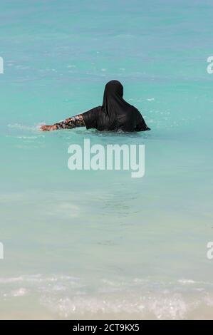 Les Maldives, femme musulmane dans l'océan avec des vêtements traditionnels Banque D'Images