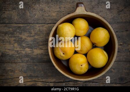 Prunes jaunes dans le bol en céramique de table en bois, studio shot Banque D'Images