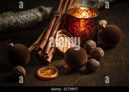 Décoration de Noël avec bougie chauffe-plat, boules d'arbre de noël, bâtons de cannelle, tranches d'oranges séchées et noix sur table en bois, prise studio Banque D'Images