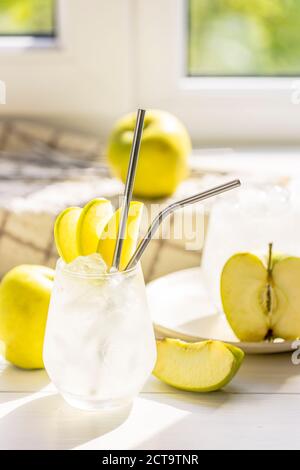 Cocktail d'été avec pomme verte et glace sur la table blanche près de la fenêtre en été ensoleillé. Image à mise au point sélective avec espace de copie Banque D'Images